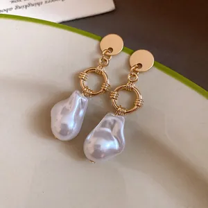 Dettaglio ravvicinato di eleganti orecchini in metallo dorato con perle barocche bianche