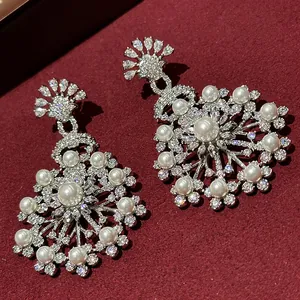 Close-up of elegant flower drop earrings with white pearls and sparkling zircons