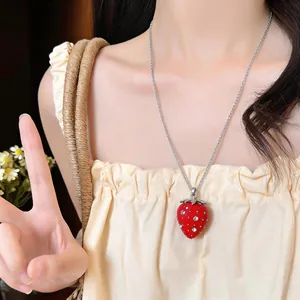 Dettaglio di una collana con ciondolo a fragola in resina rossa e strass su una modella.