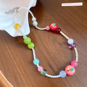 Detailed view of handmade beaded necklace with pearls and colorful apple charms