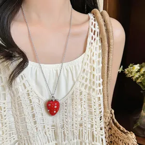 Dettaglio ravvicinato di una dolce collana con fragola in resina rossa e strass luccicanti