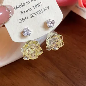 Detailaufnahme von Herz-Zirkonia-Ohrsteckern mit gelben Harzrosen und Silbernadel