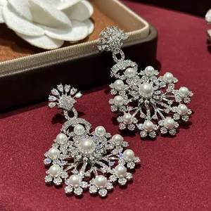 Close-up detail of silver needle flower earrings with pearls and brilliant zircons