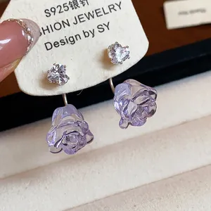 Detailaufnahme von Herz-Zirkon und violetten Harzrosen-Ohrringen mit Silbernadeln