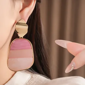Primo piano dettagliato di eleganti orecchini a goccia in acrilico rosa a strati con perni d'oro