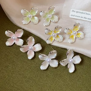 Detalle de pendientes de flores de esmalte de estilo francés con perlas de colores