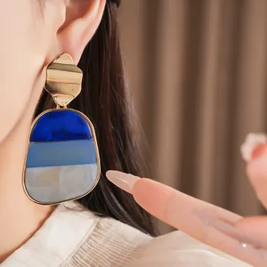 Primo piano di grandi orecchini geometrici in acrilico dal design marmorizzato blu