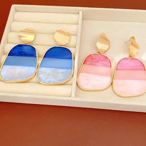 Primo piano di orecchini oversize in acrilico con sfumature blu e rosa marmorizzate