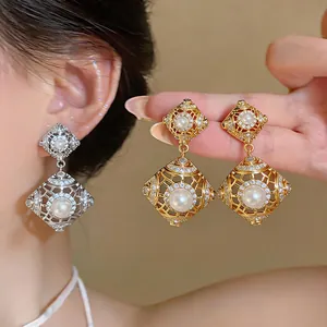 Nahaufnahme von hohlen Vintage-Ohrringen in Rautenform mit Perlen in Gold und Silber.