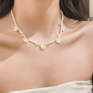 Detailed view of a sweet beaded necklace with white daisies and green leaves on a model