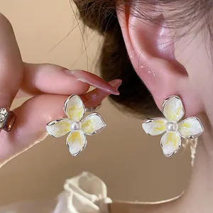 Primer plano de pendientes de flores de esmalte de estilo francés con perla