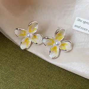 Primer plano detallado de elegantes pendientes de flor estilo francés con perlas y esmalte