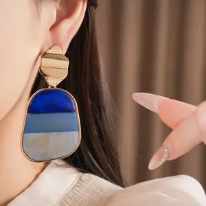 Vista dettagliata di orecchini pendenti geometrici in acrilico con motivo marmoreo blu e bianco