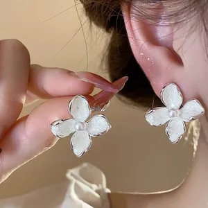 Primer plano de elegantes pendientes de flores estilo francés con perlas y esmalte