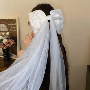 Detailed view of a sweet white satin bow hair clip with long mesh tulle streamers