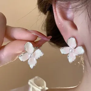 Primer plano de elegantes pendientes de flores con perlas y acabado de esmalte blanco
