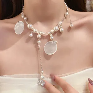 Macro view showing the detailed texture of pearl and shell dangles on the necklace
