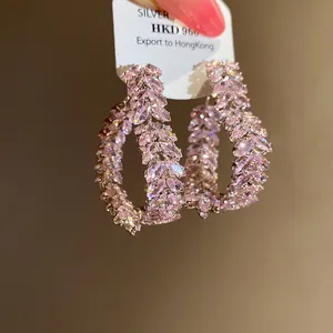 Vista detallada de elegantes pendientes de aro de circonita rosa con diseño espiga.