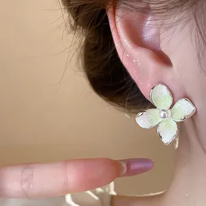 Vista detallada de un pendiente floral de estilo francés con perla y esmalte verde.