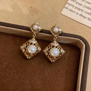 Nahaufnahme von Vintage-Ohrhängern in Rautenform mit eleganten weißen Kunstperlen.