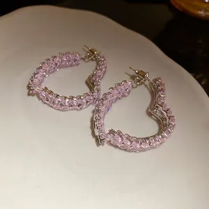 Primer plano detallado de aros de corazón plateados con circonitas rosas talla marquesa.