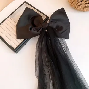 Detailed view of the black cloth bow hair clip with elegant mesh tassels.