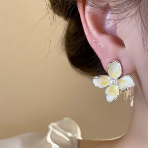 Detalle de pendientes de flor de esmalte de estilo francés con perla en la oreja