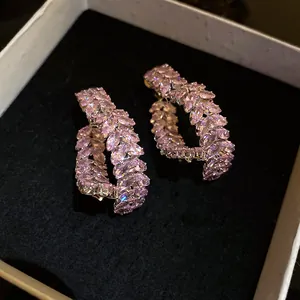 Vista detallada de elegantes pendientes de corazón de circón rosa en una caja negra
