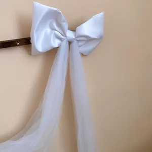 Detailed view of a white fabric bow hair clip with long elegant mesh tassels hanging down
