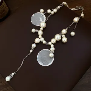 Elegant pearl beaded necklace with shell tassels and resort-style details.