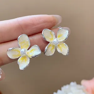 Primer plano detallado de elegantes pendientes de flores en esmalte estilo francés con perlas