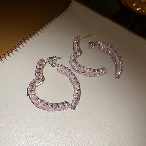 Primer plano de pendientes de aro con forma de corazón y circonitas rosas