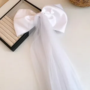 Detail view of elegant white satin bow hair clip with a long cascading mesh tulle streamer