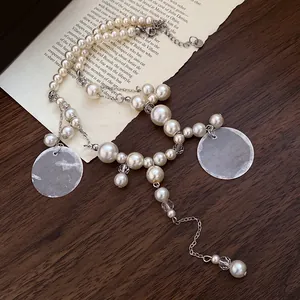 Detailed view of elegant resort style pearl necklace with shell charms and tassels