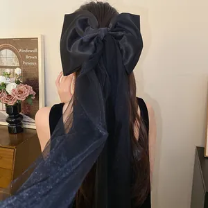 Back view of a woman wearing an elegant black fabric bow hair clip with mesh tassels