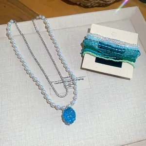 Dettaglio della collana di perle con ciondolo uva blu ghiaccio e bracciali di perline