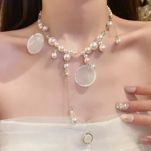Detailed view of an elegant pearl necklace featuring shell pendants and delicate tassel