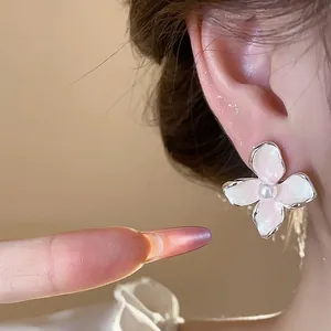 Pendientes de botón elegantes de flor blanca con perla puestos en la oreja, detalle