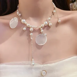 Elegant pearl and shell tassel necklace shown in detail on model's neck for a vacation look