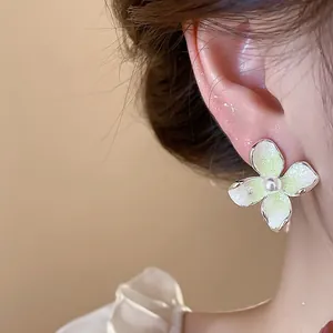 Primer plano detallado de los elegantes pendientes de flores esmaltadas con perla.