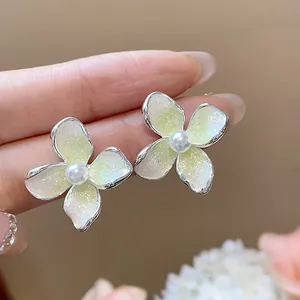 Detalle macro de elegantes pendientes de flores de esmalte con una perla blanca central