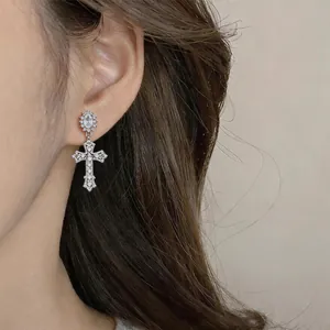 Detailopname van een elegante 18k vergulde kruisoorbel met zirkonia-inleg op het oor