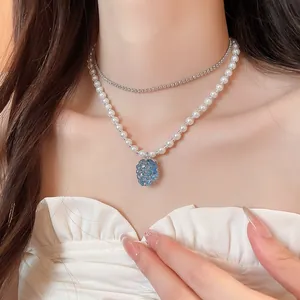 Elegante collana di perle con ciondolo a grappolo d'uva blu traslucido sul collo