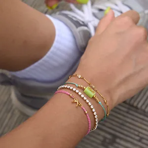 Gros plan de bracelets superposés en acier inoxydable or 18k avec perle LOVE et nœud