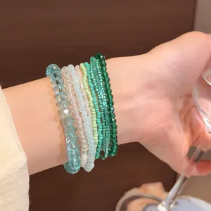 Primo piano di braccialetti di perle verdi e blu sovrapposti indossati al polso