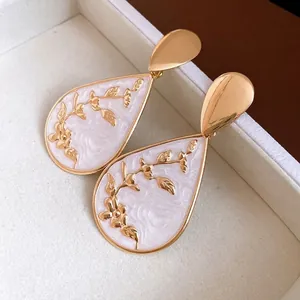 Elegant vintage water drop earrings featuring white floral enamel patterns and polished gold finish