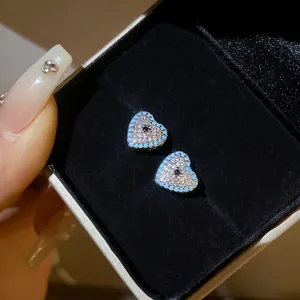 Close-up of heart-shaped evil eye earrings with zircon and turquoise detailing