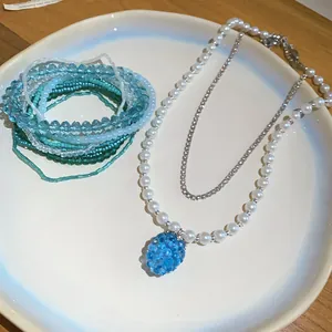 Dettaglio della collana di perle con ciondolo a uva blu e set di braccialetti blu