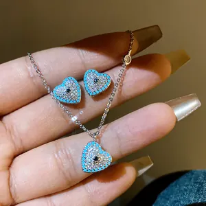 Detailed view of silver heart necklace and earrings set with turquoise and zircon