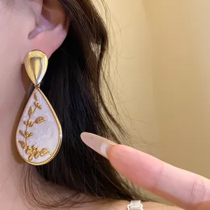 Detailed macro view of a vintage Chinese style teardrop earring with golden floral vine